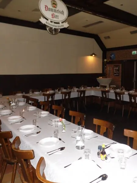 Lange gedekte tafel in de zaal, met een groot projectiescherm